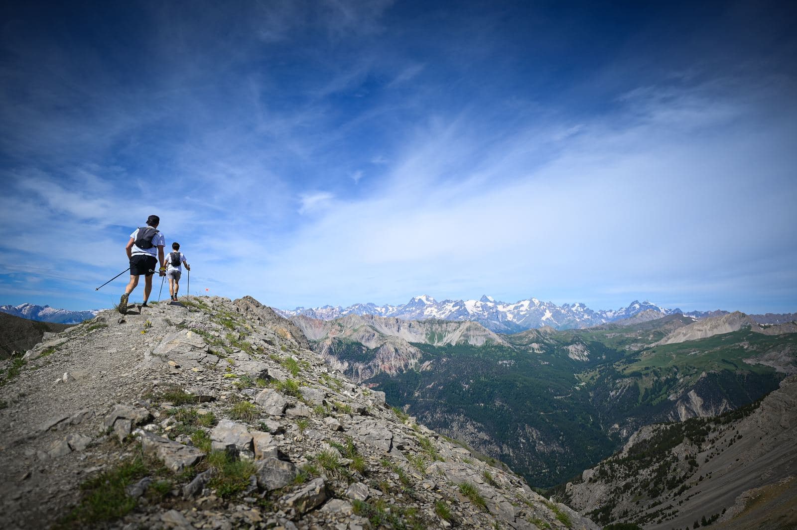 Deux coureurs au sommet d'une crête, panorama sur les Alpes