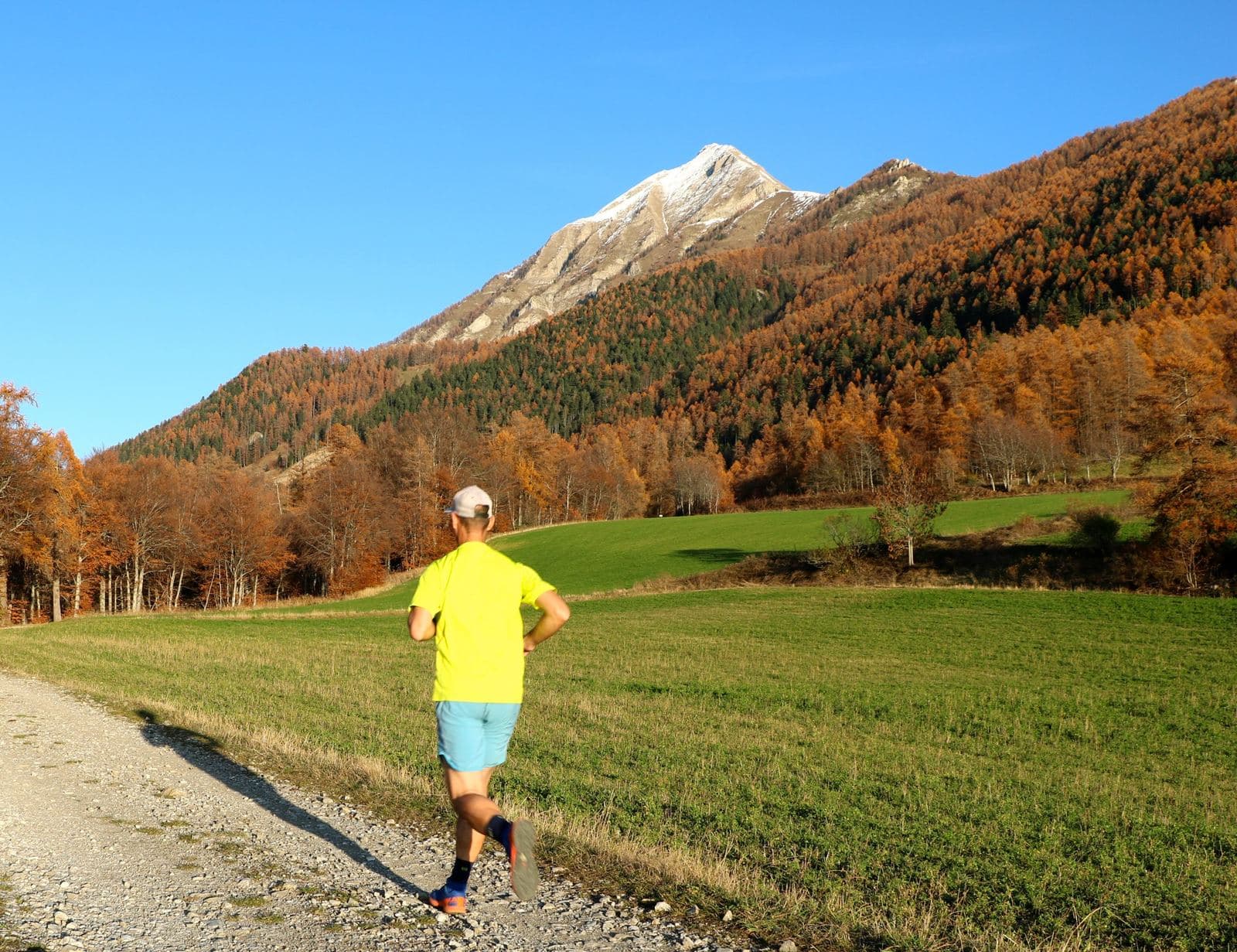 Coureur sur un chemin de campagne, sommet enneigé en arrière-plan