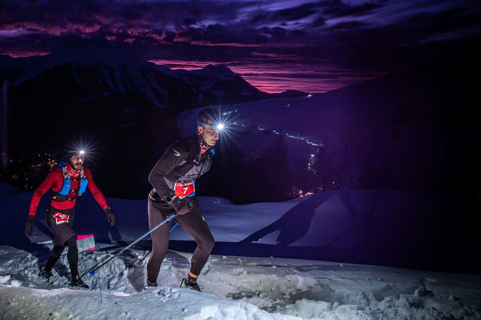 Coureurs dans la montée, lumières de la station en contrebas