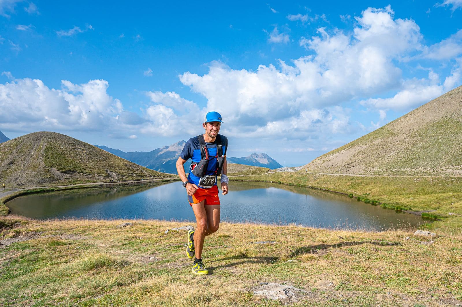 Coureur longeant un lac sous un ciel nuageux