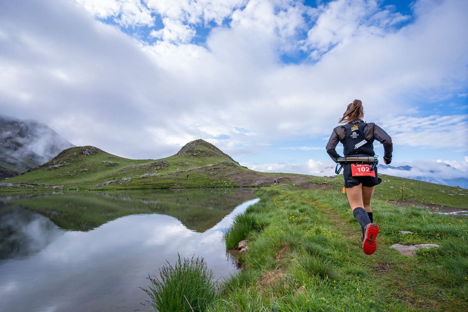 Coureuse au bord d'un lac d'altitude sous les nuages